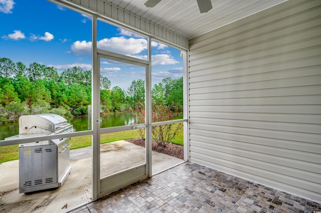 unfurnished sunroom with a water view and ceiling fan