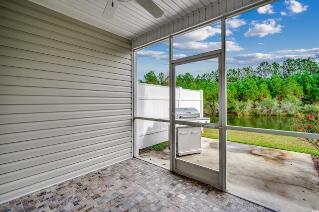 unfurnished sunroom with ceiling fan and a water view