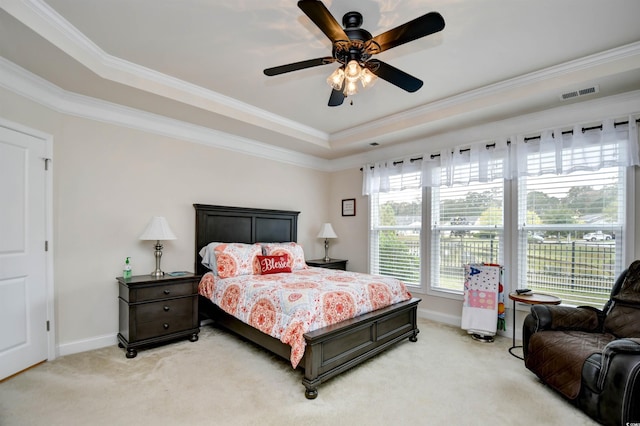 carpeted bedroom with a tray ceiling, ceiling fan, and ornamental molding