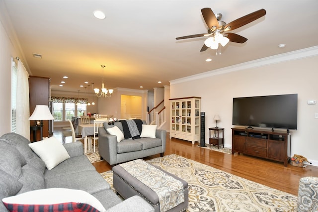 living room featuring ceiling fan with notable chandelier, light wood-type flooring, and crown molding