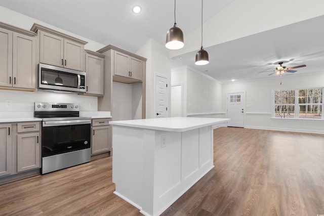 kitchen with wood-type flooring, decorative light fixtures, a center island, appliances with stainless steel finishes, and gray cabinets