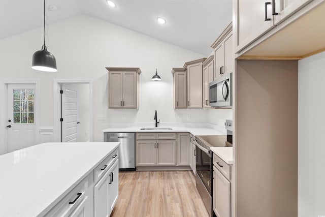 kitchen featuring sink, decorative light fixtures, high vaulted ceiling, appliances with stainless steel finishes, and light hardwood / wood-style floors