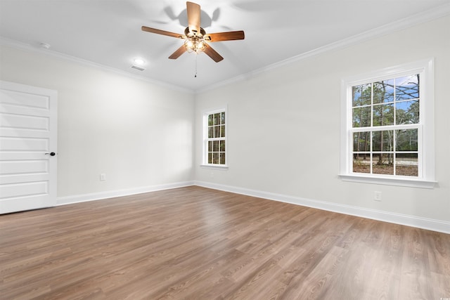 spare room with crown molding, a healthy amount of sunlight, and light wood-type flooring