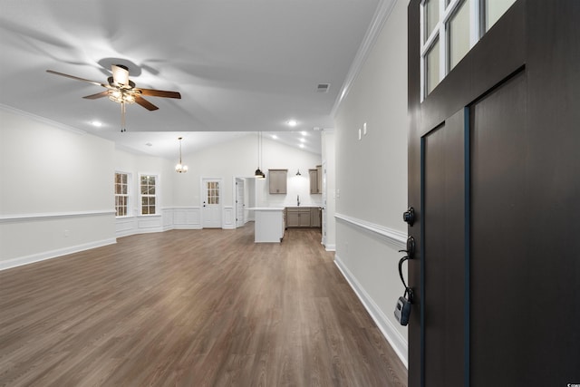 unfurnished living room featuring lofted ceiling, sink, dark hardwood / wood-style flooring, ornamental molding, and ceiling fan