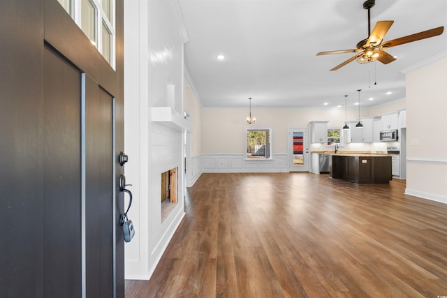 unfurnished living room with ceiling fan, dark wood-type flooring, and crown molding