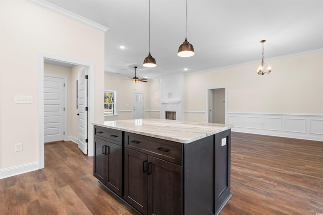 kitchen featuring dark hardwood / wood-style floors, pendant lighting, light stone countertops, and ornamental molding