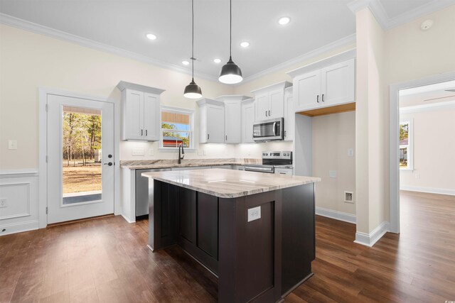 kitchen featuring white cabinetry, stainless steel appliances, decorative light fixtures, a kitchen island, and sink