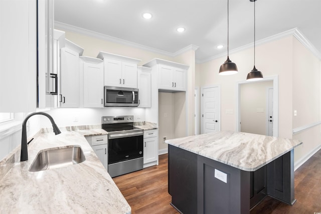 kitchen featuring appliances with stainless steel finishes, a kitchen island, white cabinetry, and decorative light fixtures