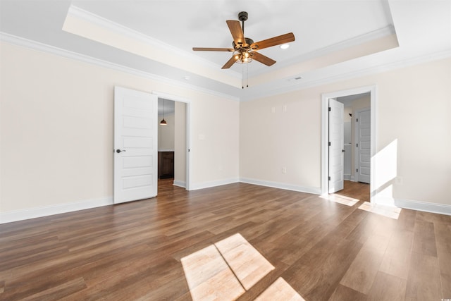 unfurnished room with a tray ceiling, ceiling fan, dark hardwood / wood-style flooring, and crown molding