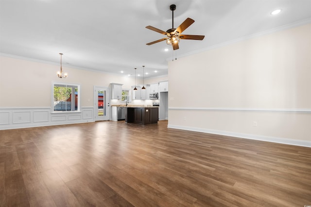 unfurnished living room with ornamental molding, dark wood-type flooring, sink, and ceiling fan with notable chandelier