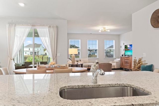 kitchen featuring plenty of natural light, light stone countertops, and a sink
