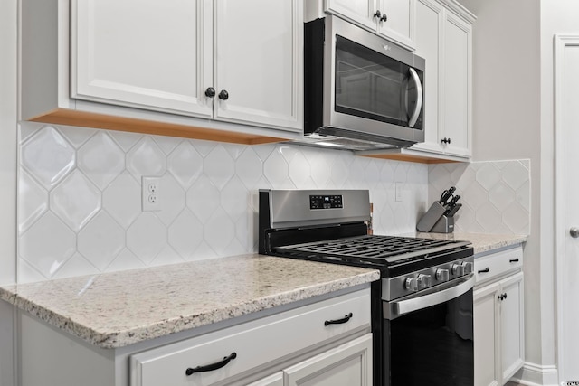 kitchen featuring white cabinets, decorative backsplash, stainless steel appliances, and light stone counters