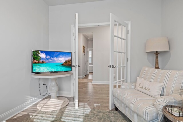 living area with french doors, baseboards, and wood finished floors