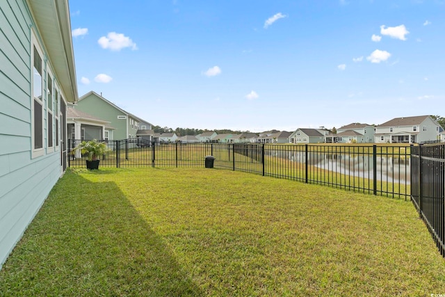 view of yard featuring a water view, a residential view, and a fenced backyard