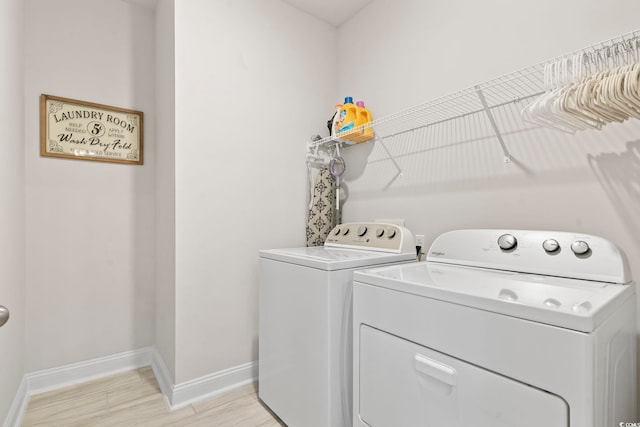 clothes washing area with washing machine and dryer and light hardwood / wood-style flooring