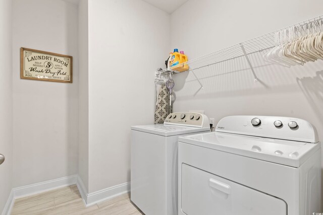 washroom with light wood-style flooring, laundry area, baseboards, and washer and clothes dryer