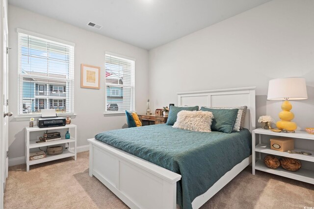 bedroom with visible vents, light colored carpet, and baseboards