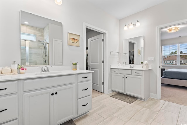 full bath featuring a sink, two vanities, a stall shower, and baseboards