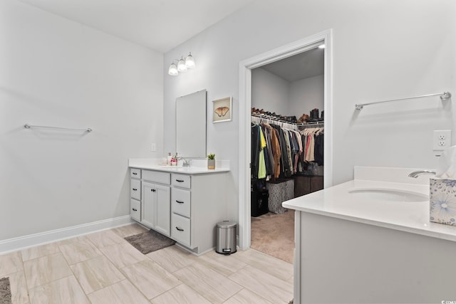 bathroom featuring a sink, a spacious closet, and two vanities