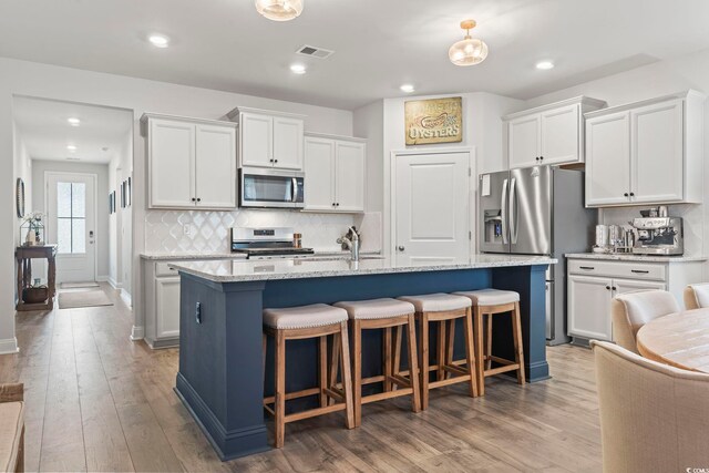 kitchen featuring light wood-type flooring, backsplash, white cabinets, and stainless steel appliances