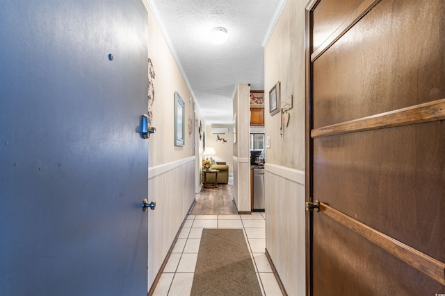 hall featuring a textured ceiling, a wall mounted AC, ornamental molding, and light tile patterned flooring