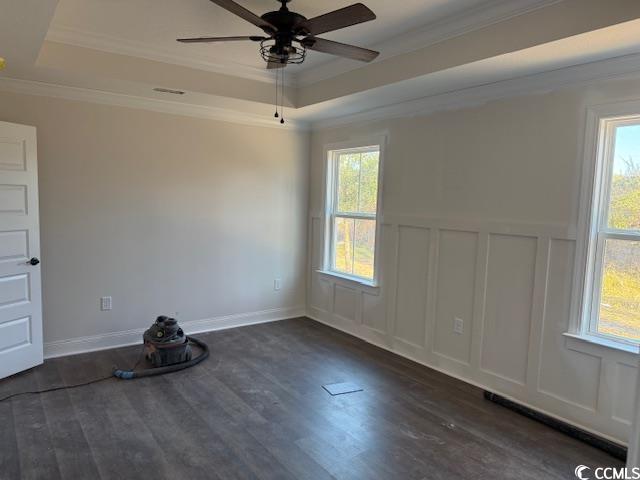 spare room featuring ceiling fan, dark hardwood / wood-style flooring, crown molding, and a tray ceiling