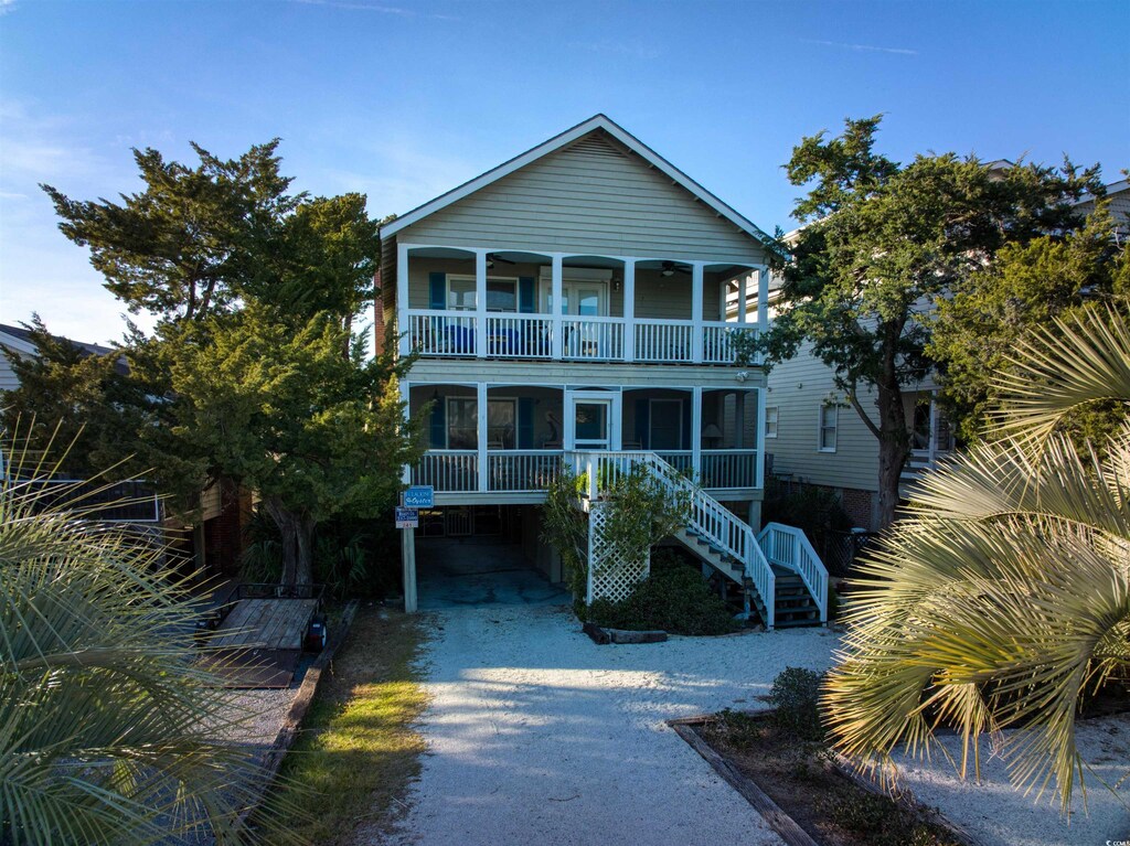 241 Atlantic Ave, Pawleys Island, SC 29585 - view of front of home with gravel driveway, a balcony, a carport, and stairway