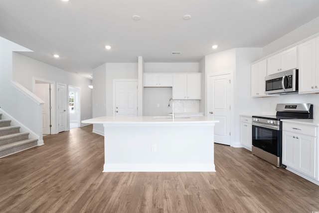 kitchen featuring stainless steel appliances, light countertops, a kitchen island with sink, and white cabinetry