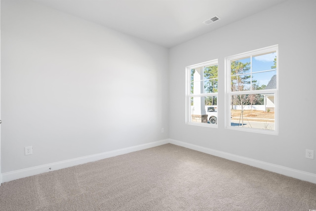 unfurnished room with carpet, visible vents, and baseboards