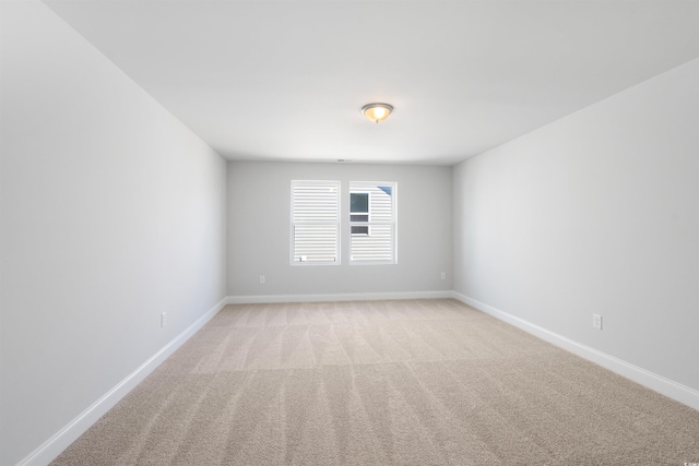 spare room with baseboards and light colored carpet