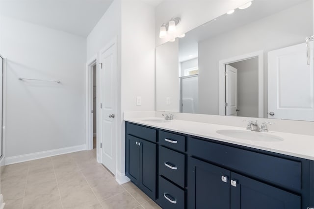 full bathroom featuring double vanity, a stall shower, tile patterned flooring, and a sink