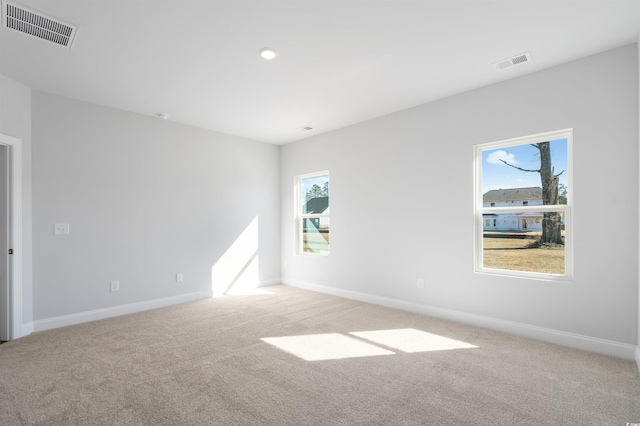 unfurnished room with visible vents, light carpet, and baseboards