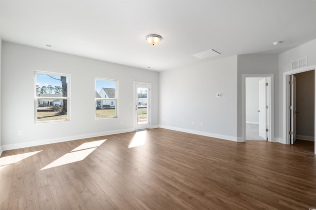 empty room featuring visible vents, baseboards, and wood finished floors