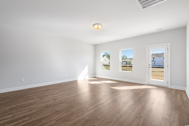 unfurnished room featuring dark wood-style floors, visible vents, and baseboards