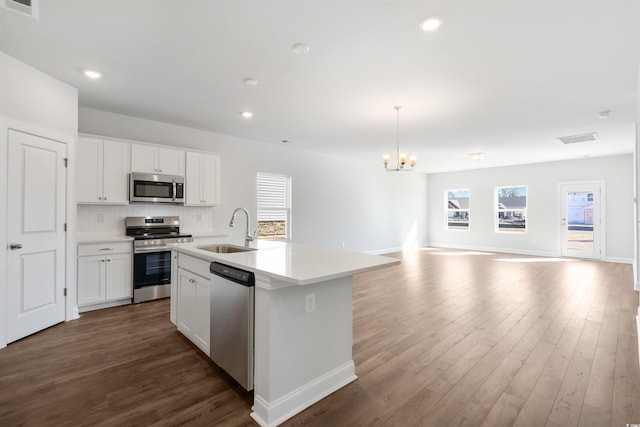 kitchen featuring white cabinets, open floor plan, stainless steel appliances, light countertops, and a sink