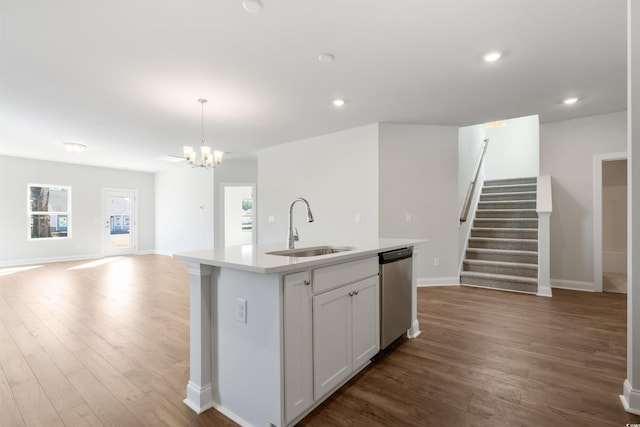 kitchen with light countertops, open floor plan, a kitchen island with sink, a sink, and dishwasher