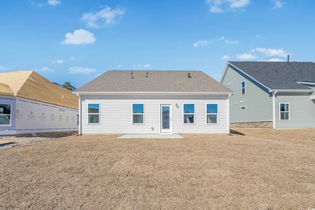 back of house with a patio area, a lawn, and roof with shingles