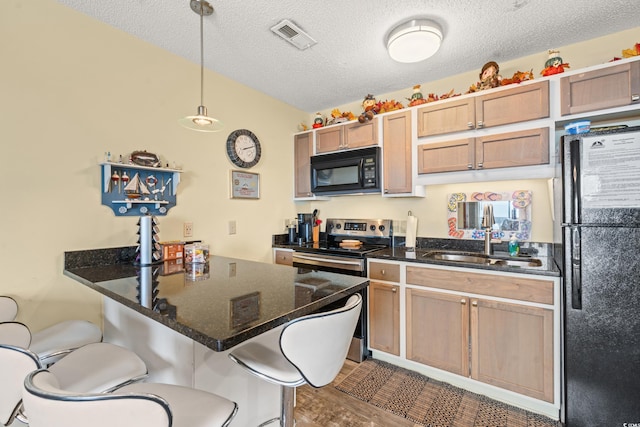 kitchen featuring fridge, sink, a breakfast bar area, and pendant lighting