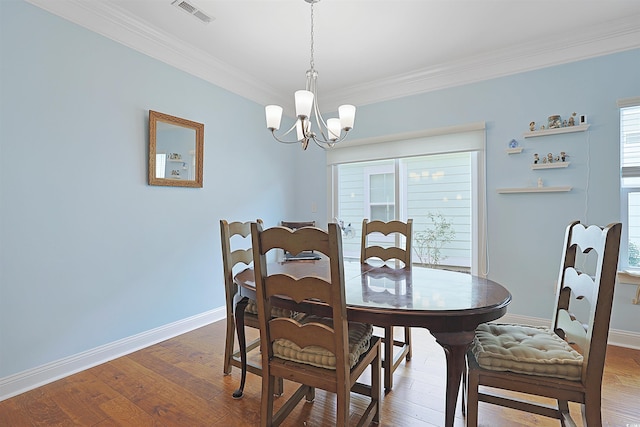 dining room with hardwood / wood-style flooring, an inviting chandelier, and ornamental molding