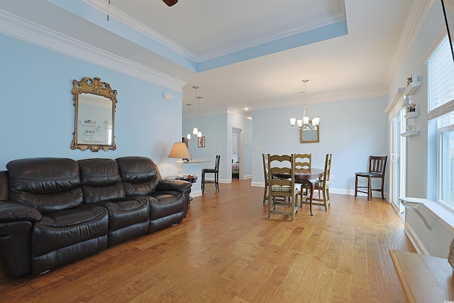 living room featuring ceiling fan with notable chandelier, crown molding, a tray ceiling, and light hardwood / wood-style flooring