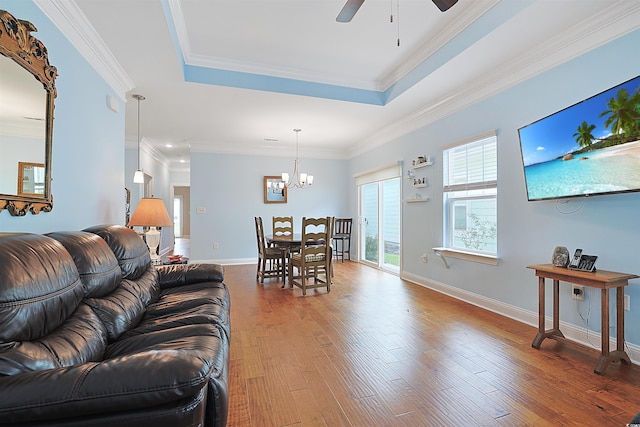 living room with hardwood / wood-style flooring, ceiling fan with notable chandelier, crown molding, and a tray ceiling