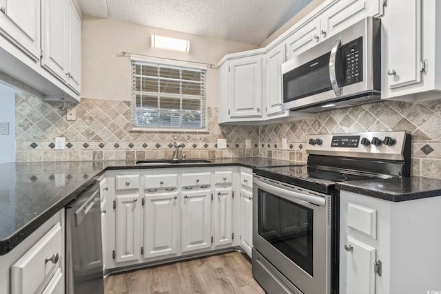 kitchen featuring sink, light wood-type flooring, white cabinets, stainless steel appliances, and a textured ceiling