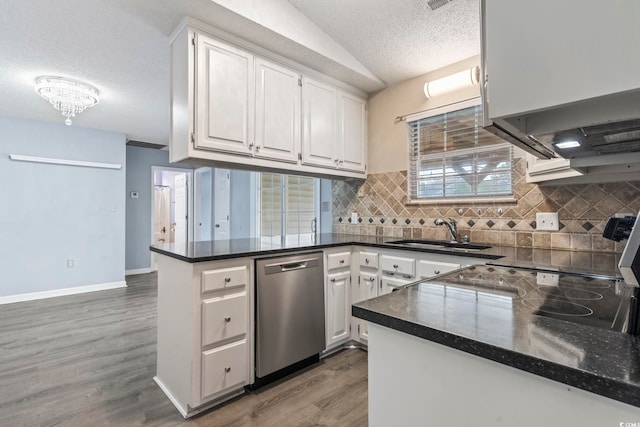 kitchen featuring sink, white cabinets, vaulted ceiling, stainless steel dishwasher, and kitchen peninsula