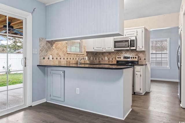 kitchen with backsplash, stainless steel appliances, a wealth of natural light, white cabinets, and kitchen peninsula