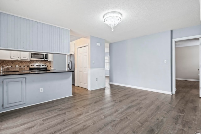 kitchen with sink, dark wood-type flooring, appliances with stainless steel finishes, white cabinetry, and decorative backsplash