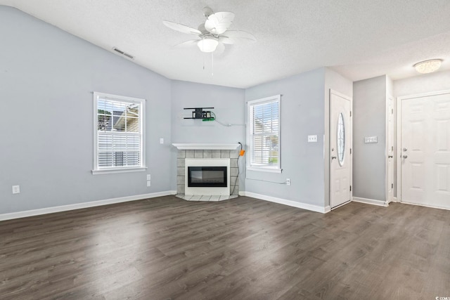 unfurnished living room with dark hardwood / wood-style flooring, a tiled fireplace, and a wealth of natural light