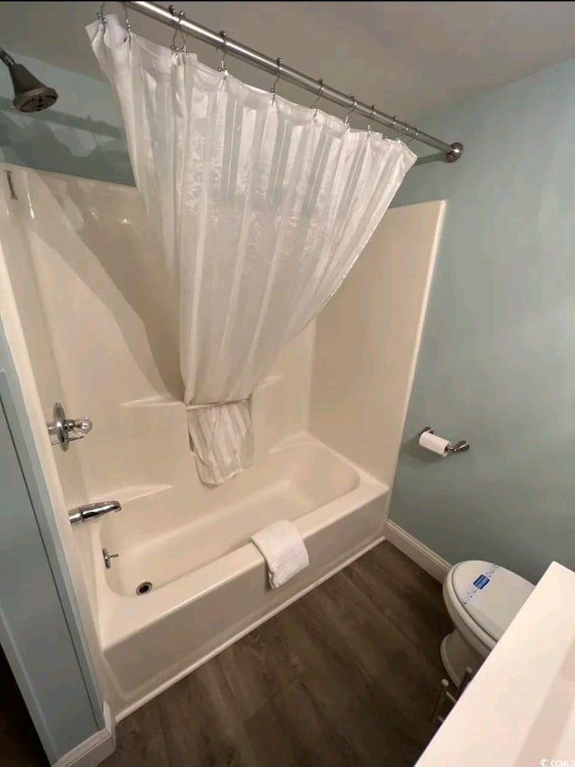 bathroom featuring wood-type flooring, shower / tub combo, and toilet