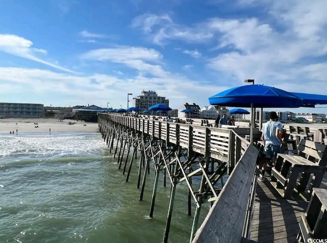 dock area with a water view and a beach view