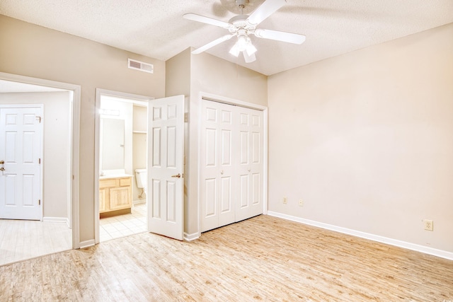 unfurnished bedroom featuring a textured ceiling, a closet, light hardwood / wood-style flooring, and ceiling fan