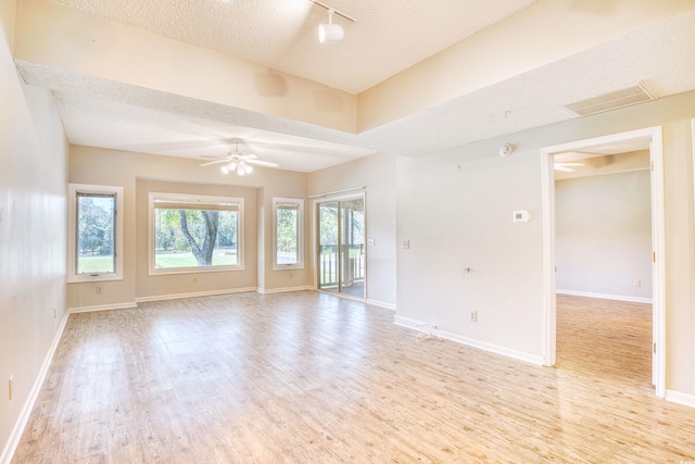 empty room with ceiling fan, light wood-type flooring, and a textured ceiling